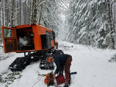 Greg Downing, with the USFS, clears the road of fallen trees, with the aid of snowcat and chainsaw